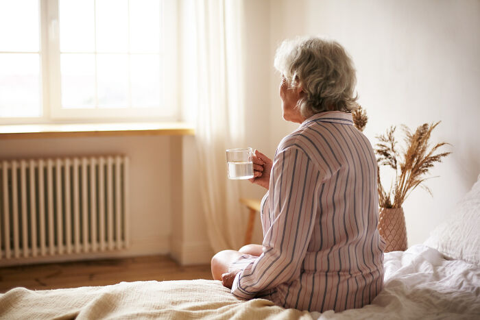 Elderly woman drinking water in bed by window real nightmare starts after waking up