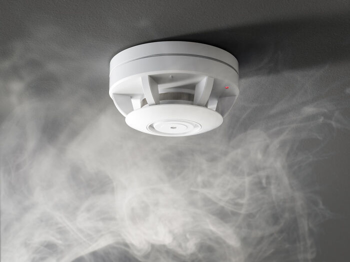 Smoke detector on ceiling with smoke around it