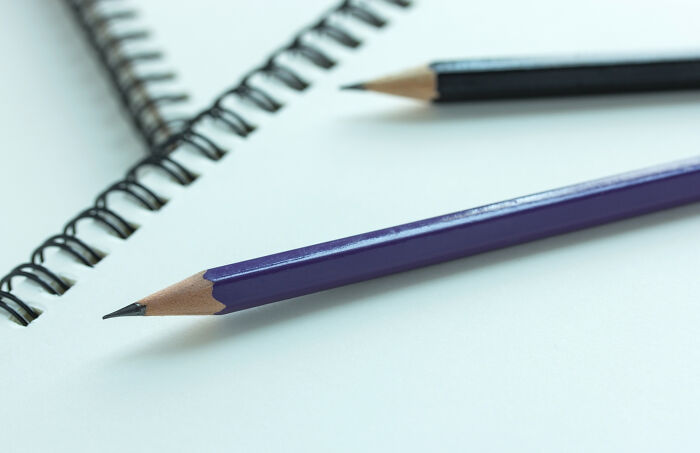 Close-up of pencil and notebook on white surface