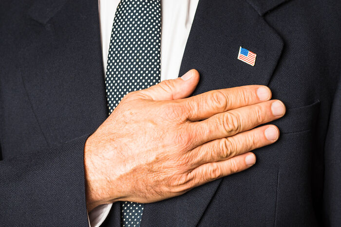 Hand over heart with American flag pin on suit jacket nightmare stories
