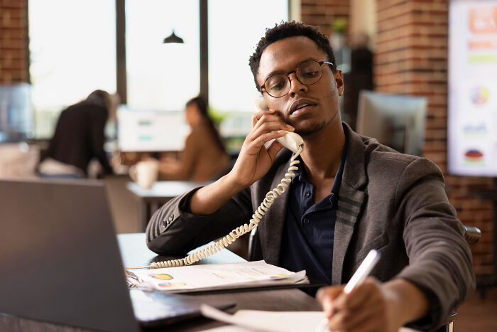 Man talking on phone and writing notes in office nightmare stories