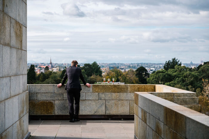 Man in suit looking over balcony at city view reflecting real nightmare thoughts