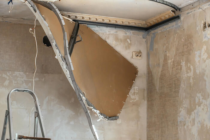 Damaged ceiling with hanging broken drywall in home showing real nightmare aftermath