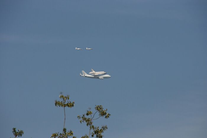 Rare moment of space shuttle riding on plane with two escort jets in clear sky