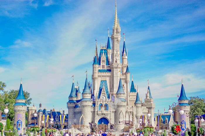 Crowded theme park castle with blue spires under a bright sky geography facts