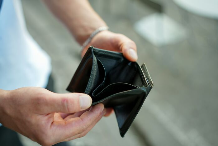 Empty wallet held in hands depicting financial struggle in society