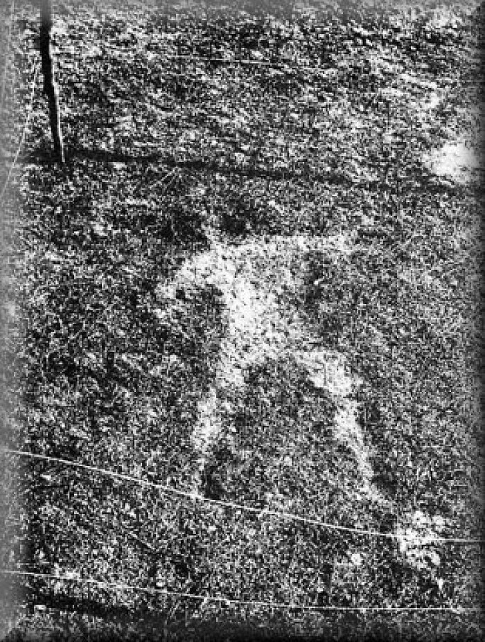 Black and white image showing mysterious figure shape in grass