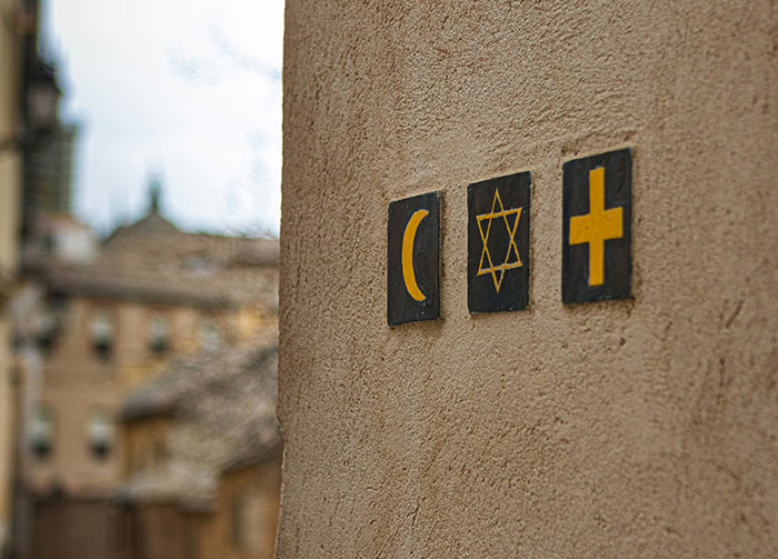Religious symbols (crescent, Star of David, cross) on a wall, representing diverse beliefs that might start arguments.
