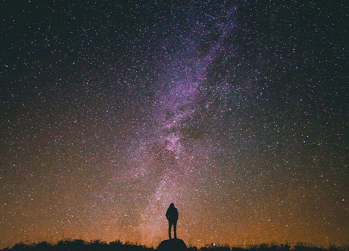 A lone person stands silhouetted under a brilliant night sky, gazing at the Milky Way. This could start arguments.