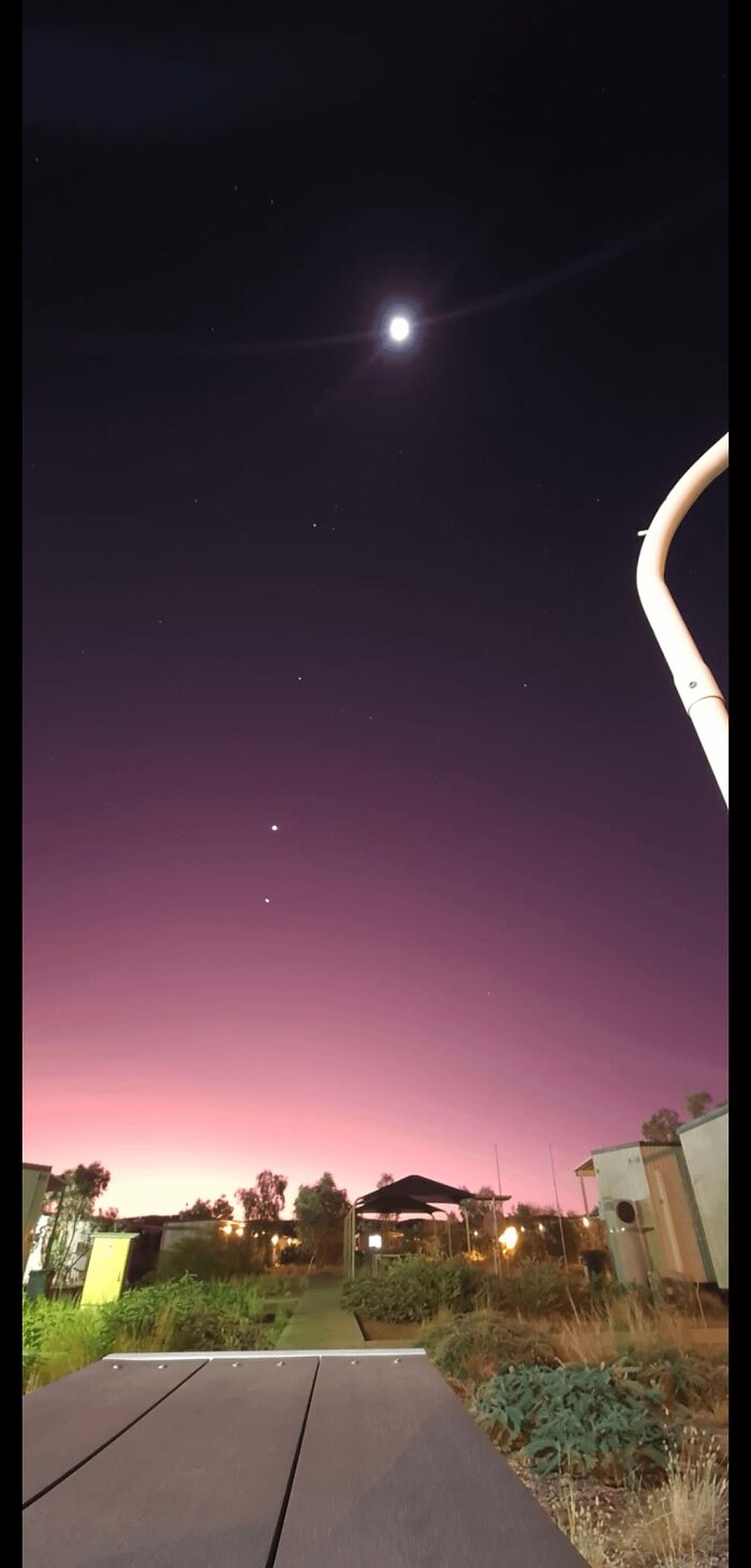 Rare night sky photo with bright moon and purple gradient over rural houses