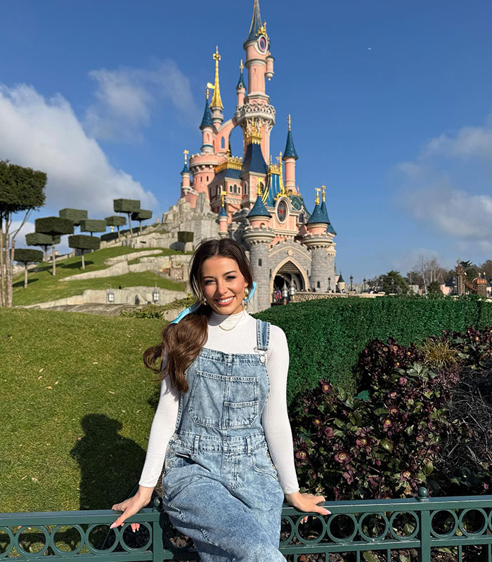 Young woman posing in front of Disneyland castle in denim dress Young woman posing in front of Disneyland castle in denim dress