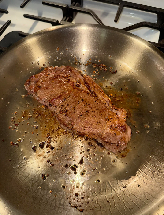 Steak searing in a pan demonstrating cooking myths related to steak frying techniques
