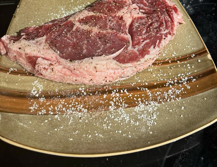 Raw steak seasoned with salt and pepper on a plate, illustrating cooking myths about meat preparation