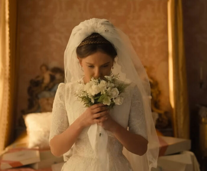 Millie Bobby Brown in wedding dress holding bouquet
