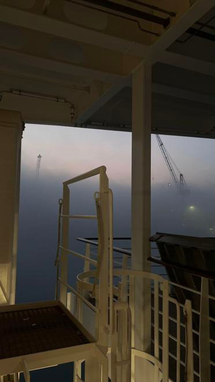 A foggy, deserted ship deck overlooking a vast, misty sea with cranes, a haunting liminal space.