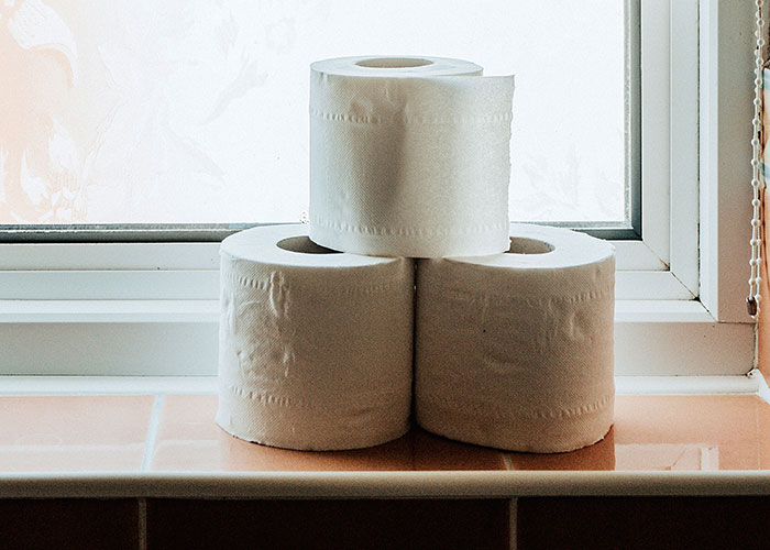 Three rolls of toilet paper stacked on a bathroom windowsill Three rolls of toilet paper stacked on a bathroom windowsill