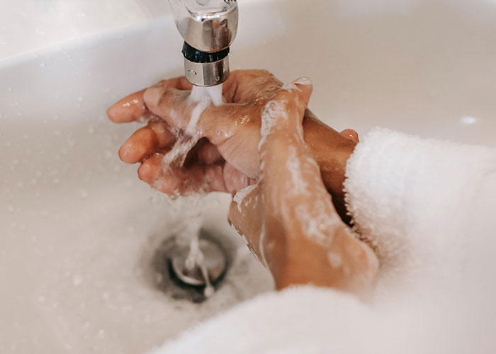 Hands being washed under running faucet focusing on hygiene and cleanliness Hands being washed under running faucet focusing on hygiene and cleanliness