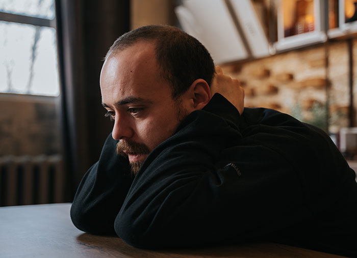 Man looking contemplative and upset indoors representing family conflict Man looking contemplative and upset indoors representing family conflict