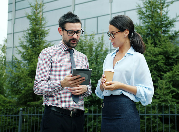 A new hire discussing management's illegal shenanigans with a colleague outdoors.