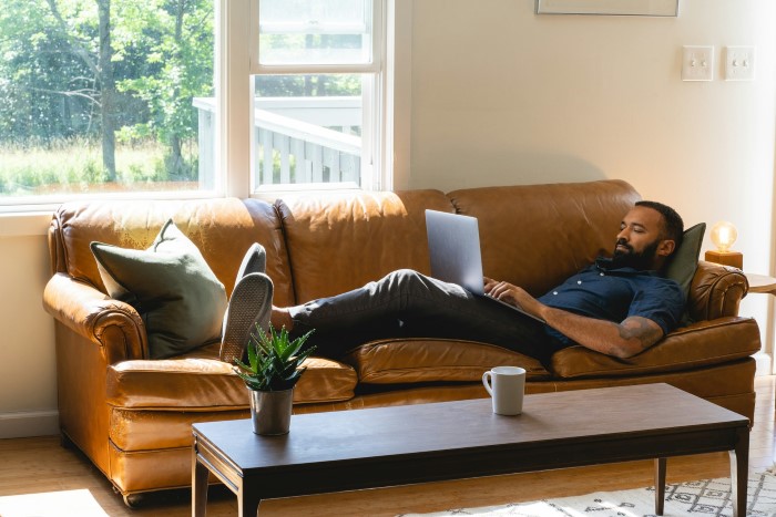A new hire relaxing on a couch with a laptop, highlighting the contrast with illegal shenanigans management.