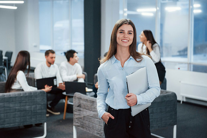 A smiling new hire with a laptop in an office, confident against illegal shenanigans management.