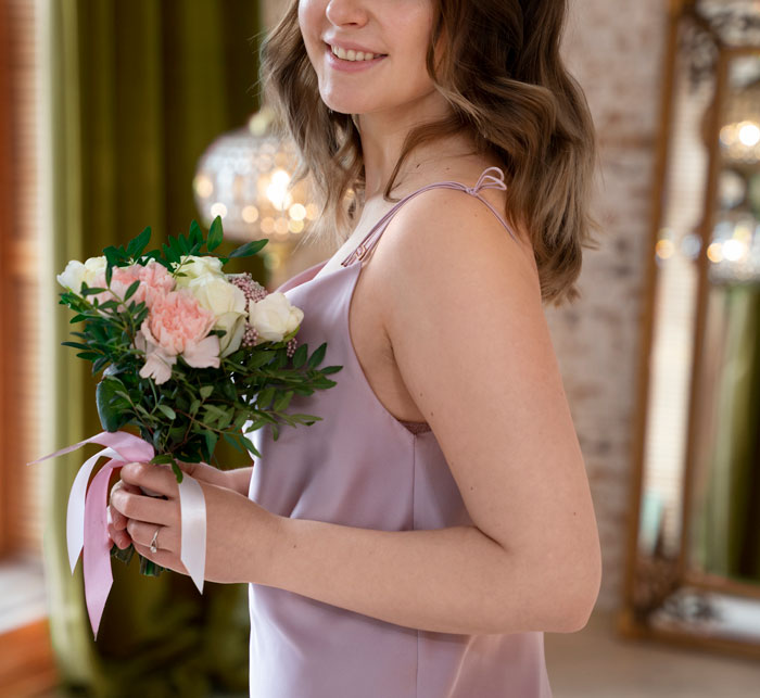 Woman holding bouquet dressed as maid of honor for wedding event