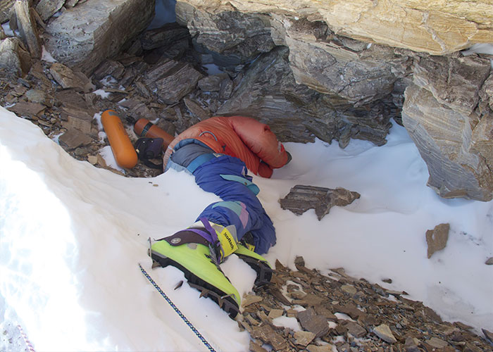 Green Boots frozen body on Mount Everest, partially buried in snow against a rocky alcove, with mountaineering boots visible.