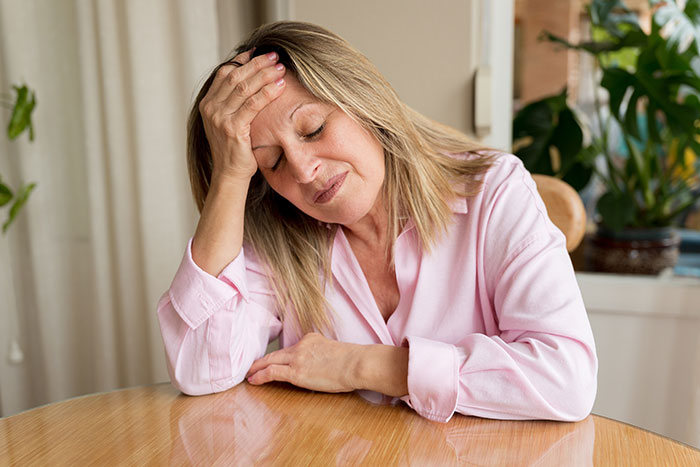 Stressed woman holding head, depicting MIL haunting couple over not having kids