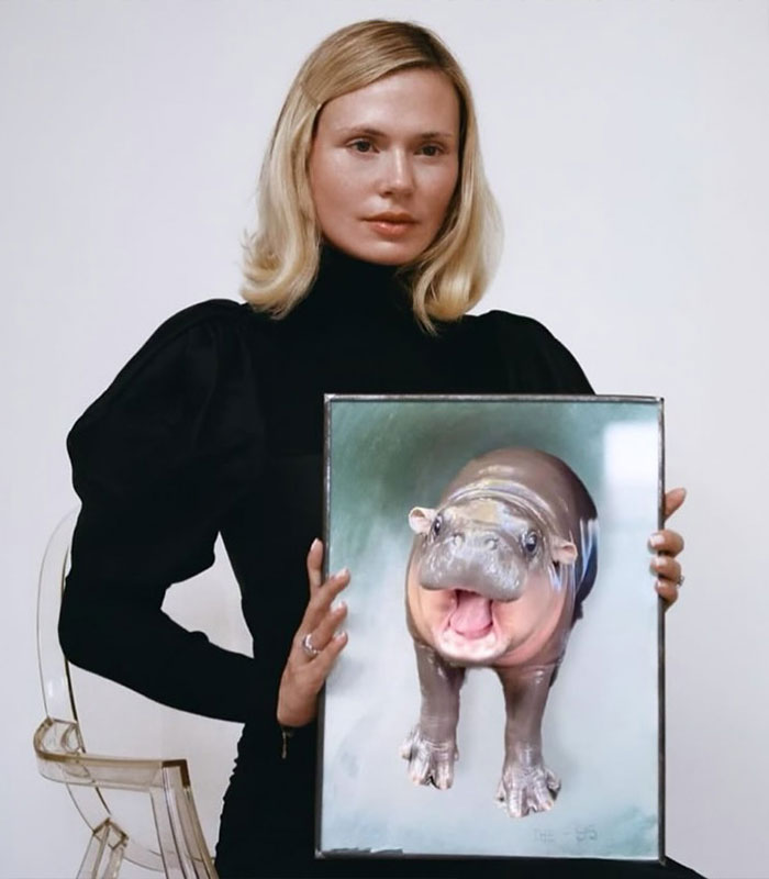 US influencer sitting with a framed photo of a hippo in a black outfit US influencer sitting with a framed photo of a hippo in a black outfit