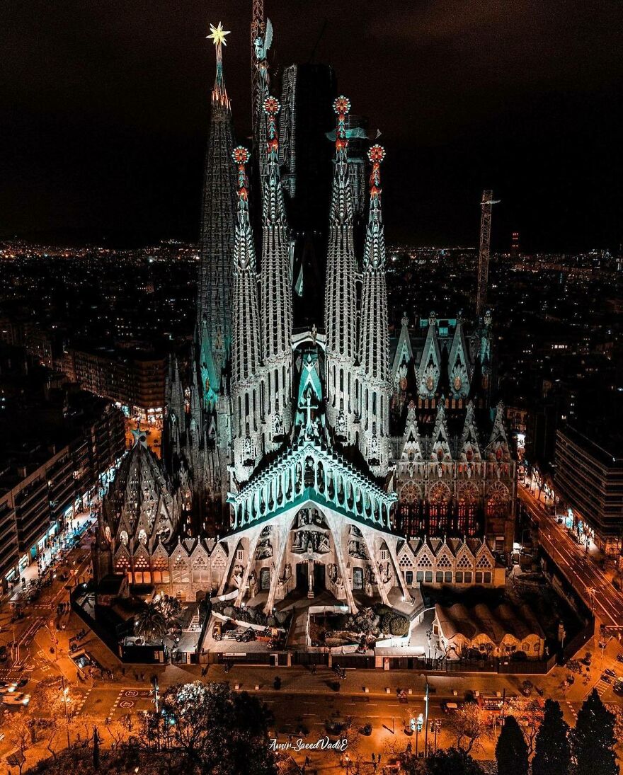 Illuminated towering Sagrada Família cathedral at night amidst city lights