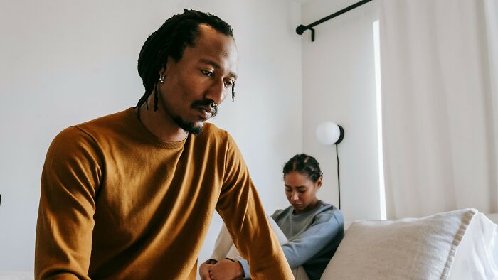 Couple sitting apart looking upset in living room conflict