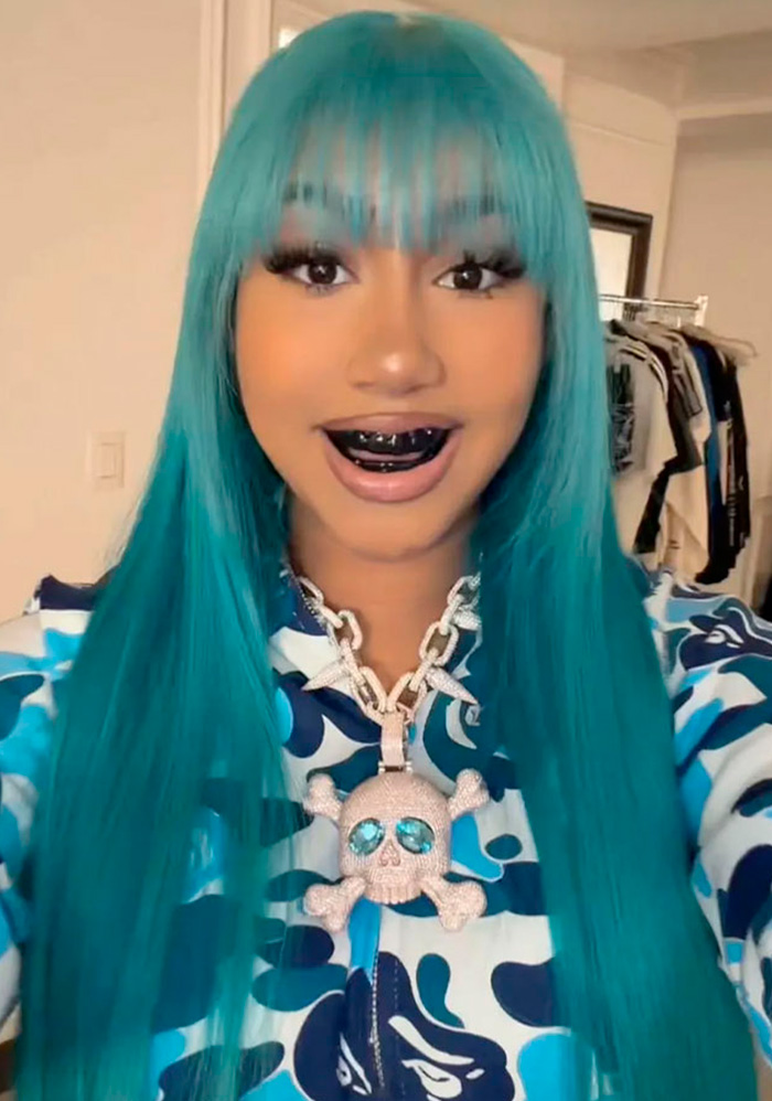 Woman with teal hair wearing blackened teeth grills and skull necklace Woman with teal hair wearing blackened teeth grills and skull necklace