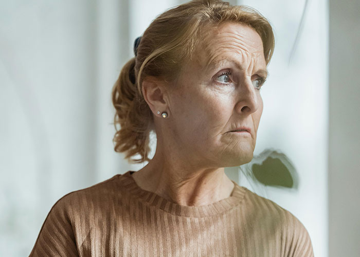 Contemplative older woman looking out window, reflective mood