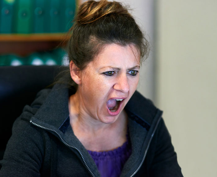 Furious woman yelling indoors representing Karen rage