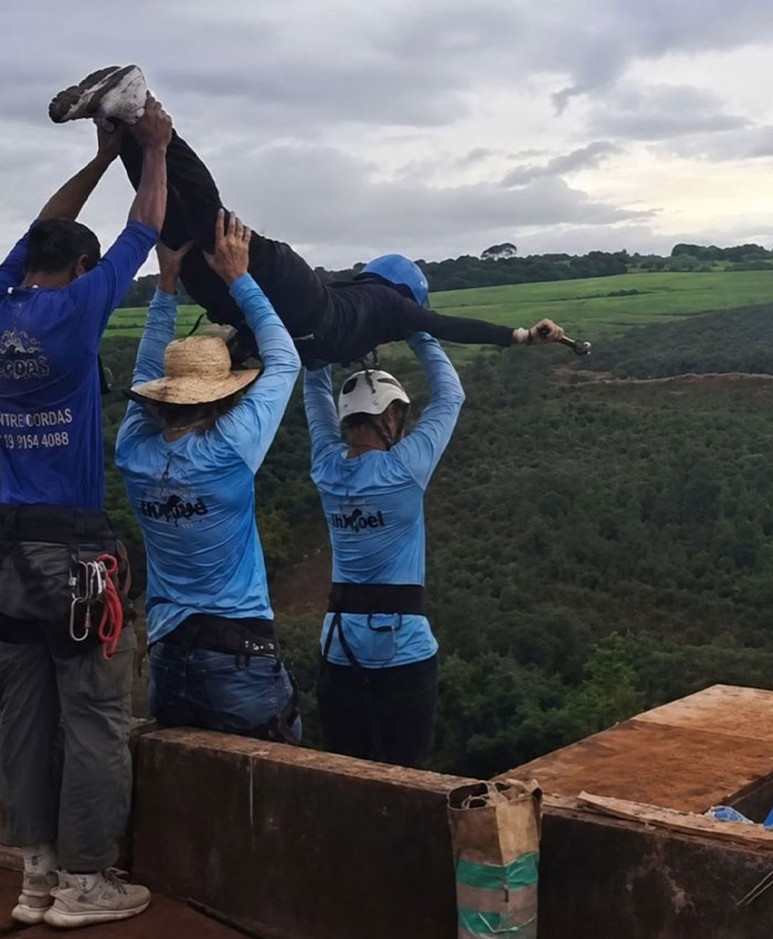 Bungee jumper being lifted by staff near a cliff during bungee jump setup Bungee jumper being lifted by staff near a cliff during bungee jump setup