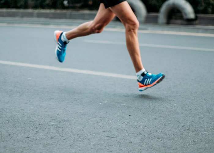A jogger's legs in blue and orange running shoes, illustrating the jogger pushing woman in front of bus event. A jogger's legs in blue and orange running shoes, illustrating the jogger pushing woman in front of bus event.