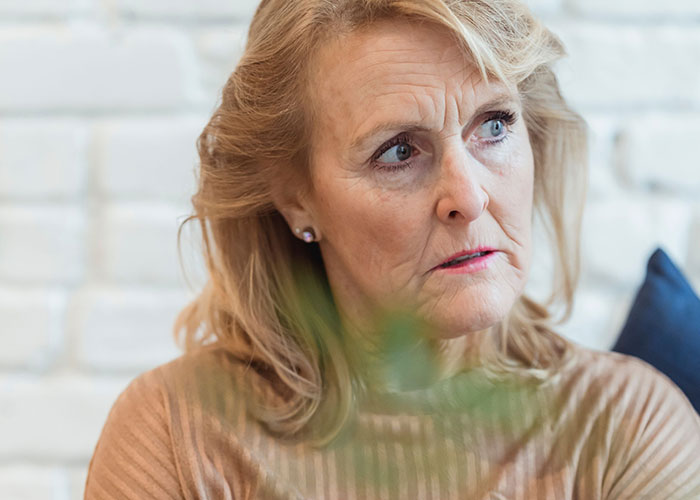 An older woman with a worried expression looks to the side, contemplating when kids can't keep contact with parents.