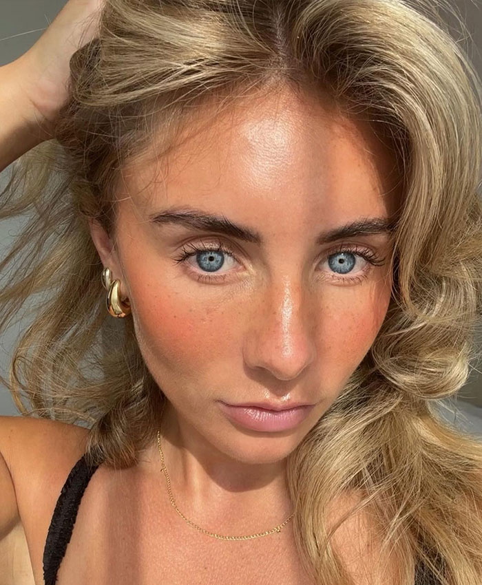 Close-up of Bonnie Blue with bright blue eyes, natural makeup, and golden accessories, capturing the baby shower excitement.