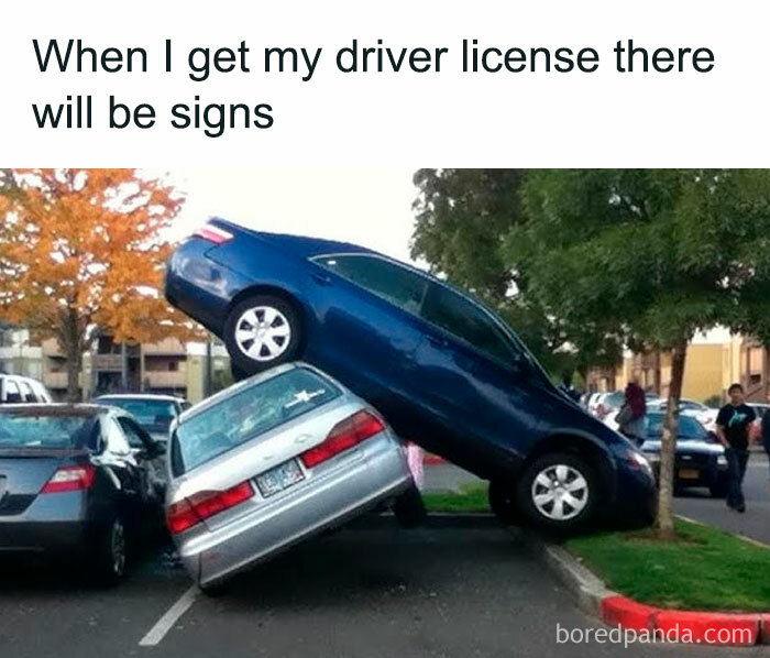 A cringe image of a blue car parked precariously on top of a silver car in a parking lot.