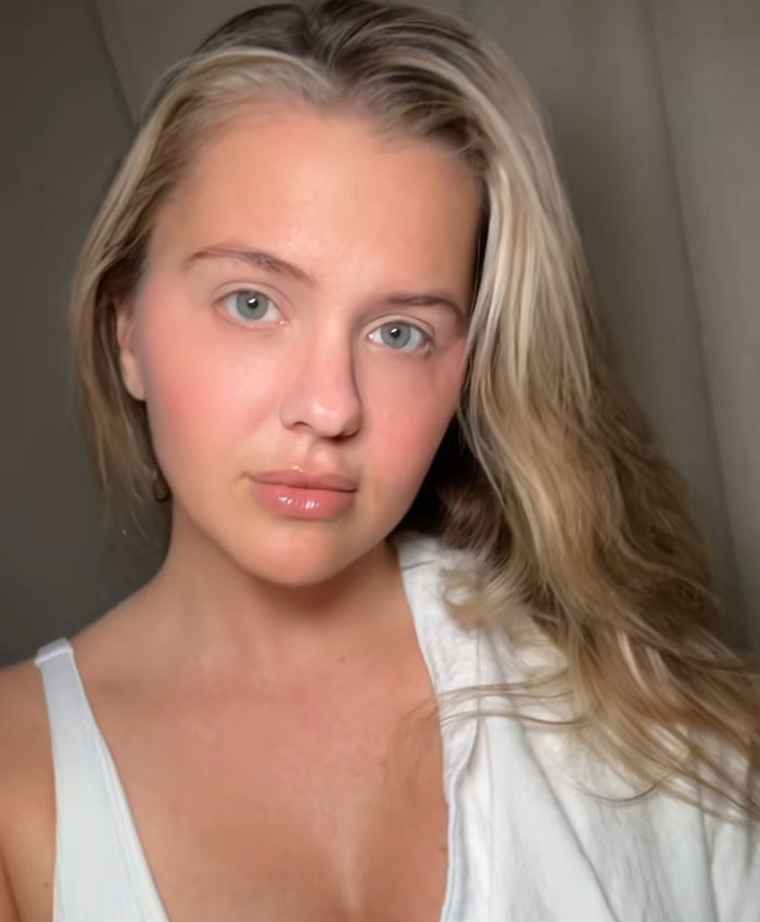 A woman with blonde hair and a white tank top looks at the camera. She participated in the Lily Phillips Backdoor Challenge.
