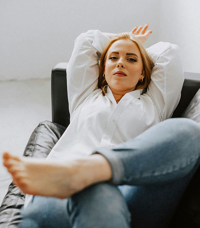 Woman relaxing on couch looking confident and offended Woman relaxing on couch looking confident and offended