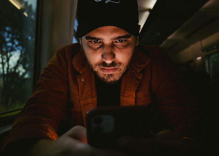Man focused on smartphone late at night