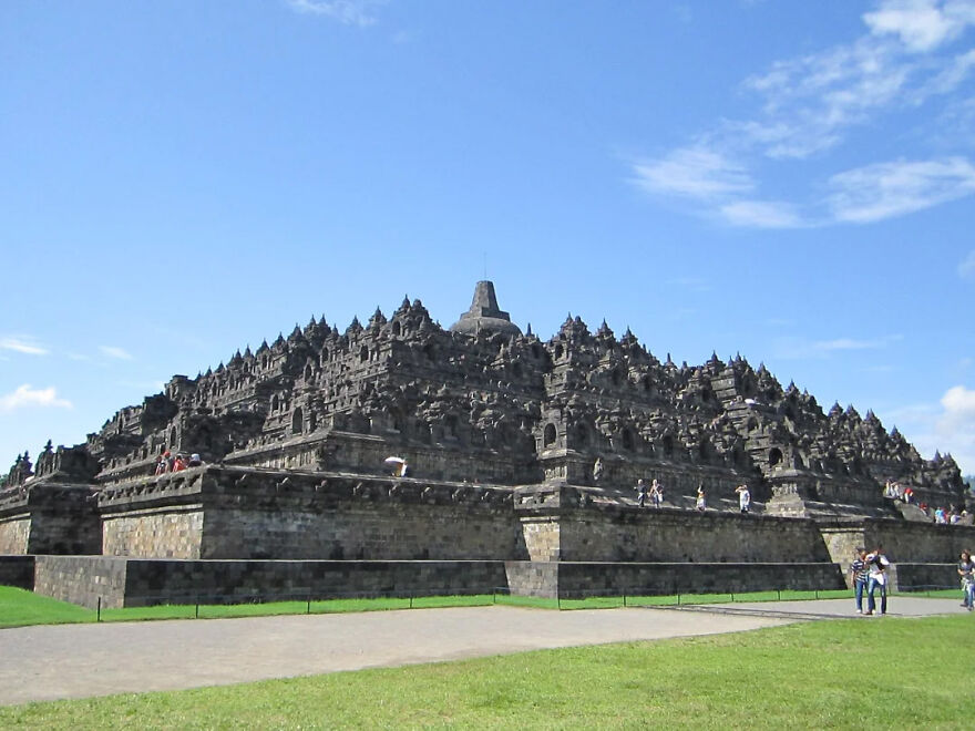 Large stone Borobudur Temple complex with intricate carvings under blue sky