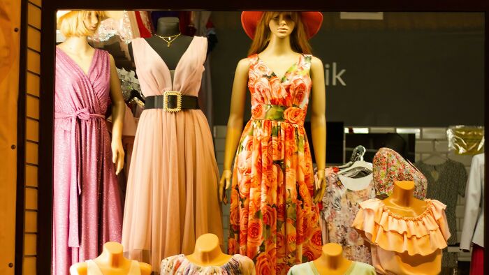 Mannequins displaying spring and summer fashion dresses in store window