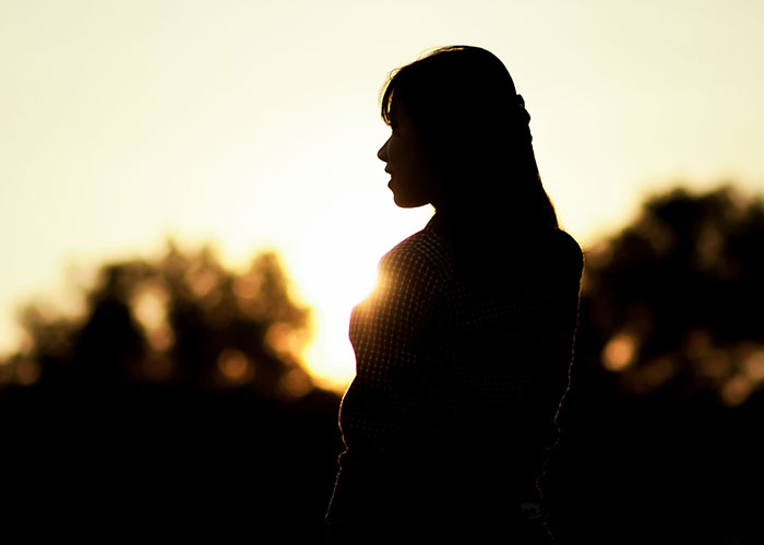Silhouette of a woman at sunset, reflecting on popular kids who peaked in high school