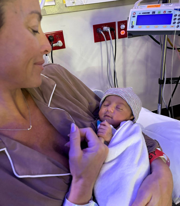 Woman holding a swaddled newborn baby, born to the wrong parents after an IVF mix-up. Woman holding a swaddled newborn baby, born to the wrong parents after an IVF mix-up.