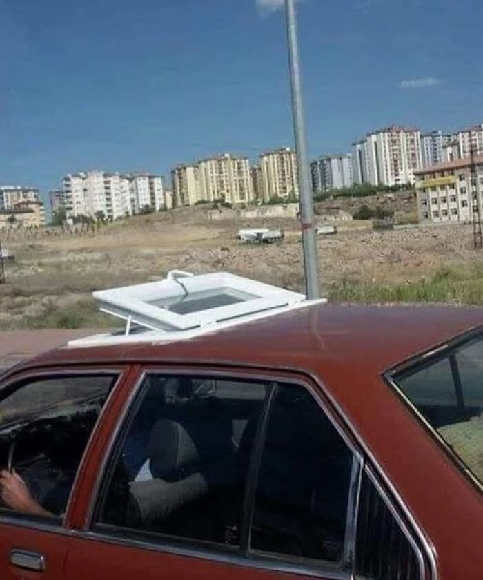 A car with a window frame strapped to its roof, a clever example of transportation in Slavic Science.