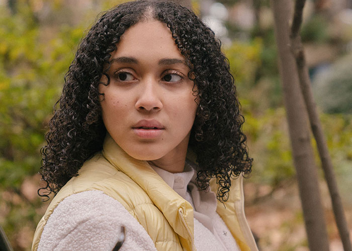 A young woman with curly hair looking to the side, contemplating things close friends commit that broke people's trust forever.