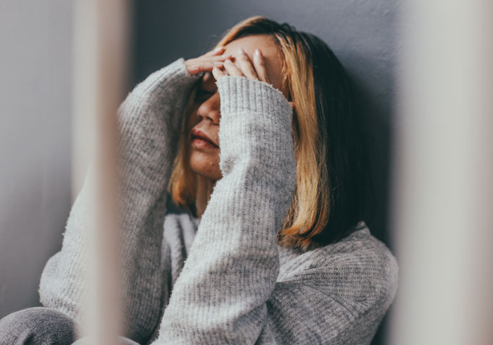 A distressed woman with her hands on her head, possibly reacting to unexpected DNA testing results.