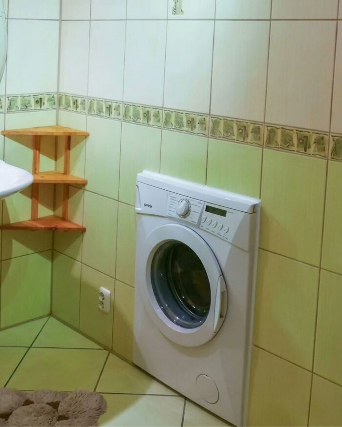 A washing machine installed in a small bathroom corner, illustrating practical Slavic Science solutions.